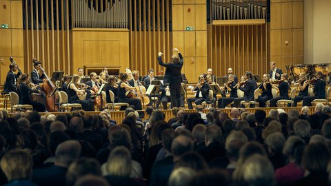 An orchestra on a stage with a conductor.