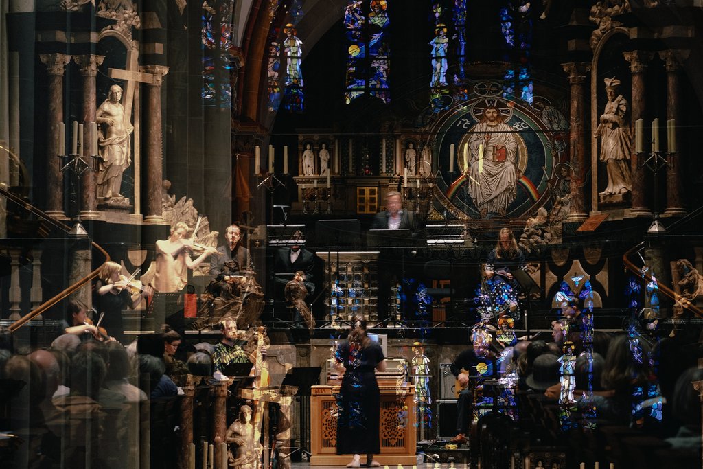 Ein Ensemble spielt in einer Kirche. überlagert von Bildern und Buntglasfenstern der Kirche