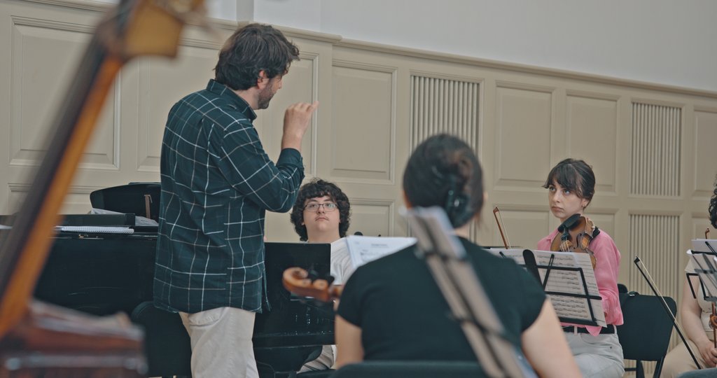 Musiker:innen bei einer Orchesterprobe mit einem Klavier Solisten.