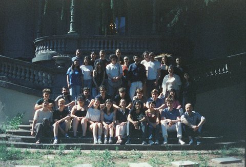 A group of people sitting and standing on steps in front of a large building, all facing the camera.  © private
