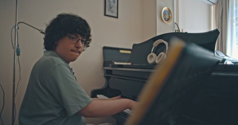 A person plays piano in a room with headphones on the instrument. The atmosphere appears creative and relaxed.  © Jasper Techel
