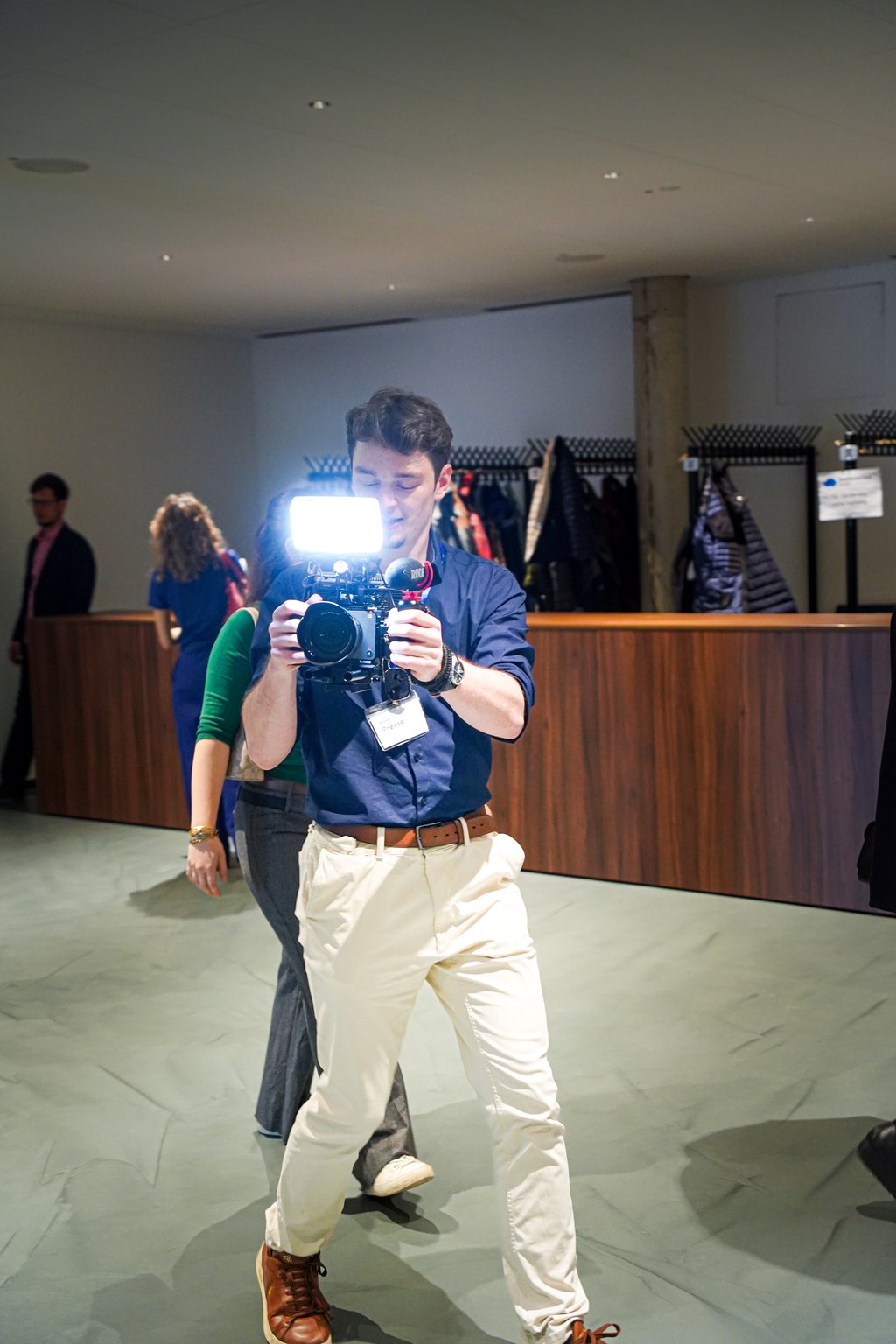 A photographer in a blue shirt takes a photo with a bright flash in a modern indoor setting.
