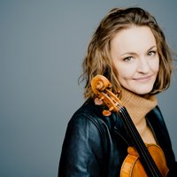 A woman with a violin, wearing a leather jacket. The background is light gray. She has a gentle smile and medium-length hair.